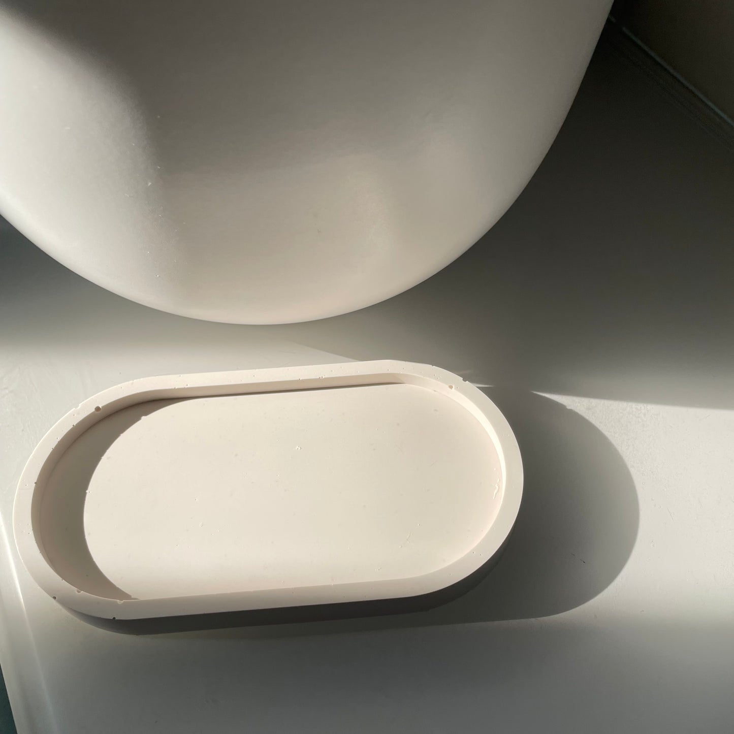 Picture of a modern and aesthetic white oval tray on a shelf.